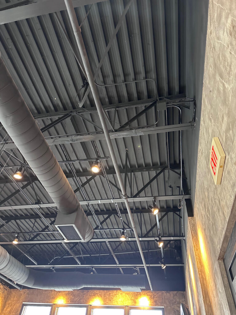 Exposed ductwork under open-web steel joists – Alltech HVAC commercial installation